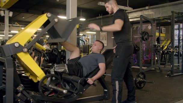 Ung man med protes ben med hjälp av ben press maskin i gymmet — Stockvideo