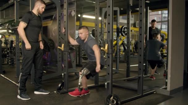 Zdravotně postižený mladý muž s instruktorem cvičení v tělocvičně — Stock video