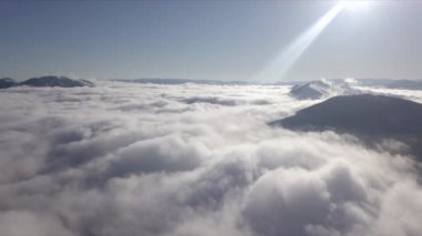 Dağların tepeleri kar ve bulutlarla kaplı güzel bir manzara.