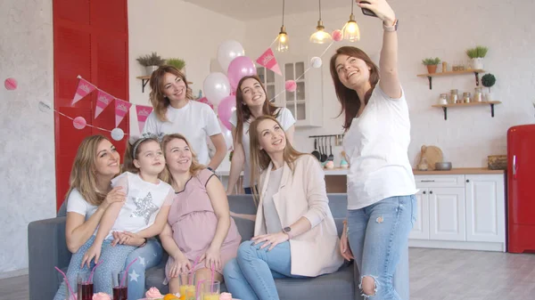 Bebek partisinde grup fotoğrafı çeken kadınlar.