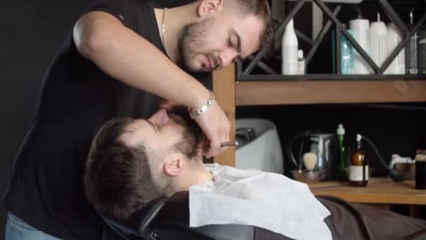 Κομμωτήριο ξυρίσματος λαιμό του πελάτη με ξυράφι — Αρχείο Βίντεο