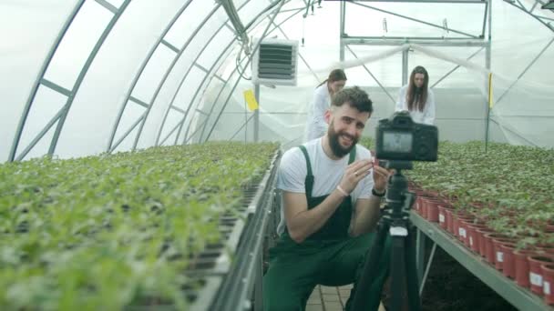 Mladý zemědělec nahrává video ve skleníku — Stock video