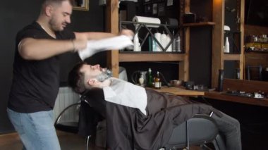 Berber müşterinin yüzünü havluyla örtüyor.