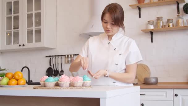 Woman decorating cupcakes in kitchen — Stock Video