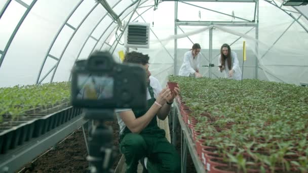 Mladý zemědělec nahrává video ve skleníku — Stock video