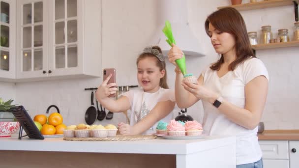 Moeder en dochter glazuur cupcakes en het hebben van video call — Stockvideo