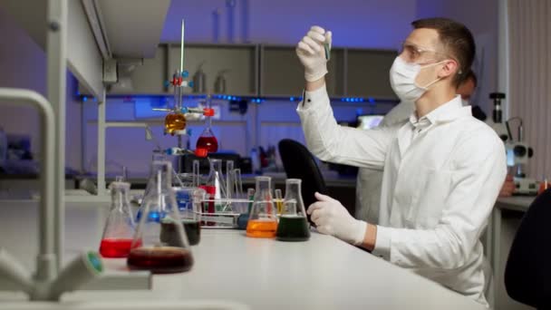 Young scientist mixing colored liquids — Stock Video