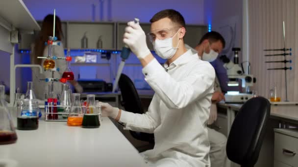 Jovem cientista misturando líquidos coloridos — Vídeo de Stock