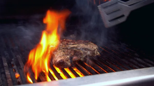 Człowiek zamieniający kawałek grillowanego mięsa w ogień — Zdjęcie stockowe