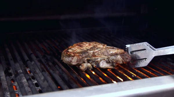 Człowiek obracający kawałek grillowanego mięsa — Zdjęcie stockowe