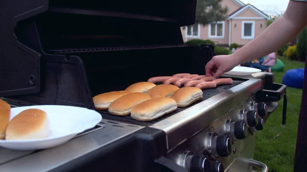 Kolbászt grillezett hot doghoz forgató személy — Stock Fotó