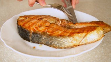 Mutfakta kızarmış somon bifteği kesen kişi. 