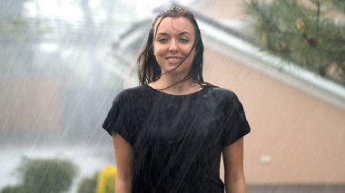 Young woman enjoying rain in garden at raining day clipart