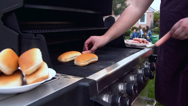Osoba obracająca kiełbaski na hot doga na grillu — Zdjęcie stockowe