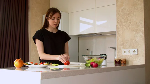 Wanita muda memotong tomat segar di dapur — Stok Foto