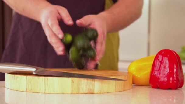 Man gooit komkommers op houten plank — Stockvideo