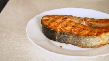 Kızarmış somon bifteği kesen kişi.