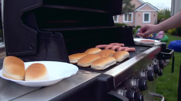 Człowiek przygotowuje hot dogi na grillu — Wideo stockowe