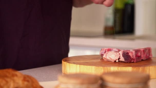 Чоловік готує стейк на кухні — стокове відео
