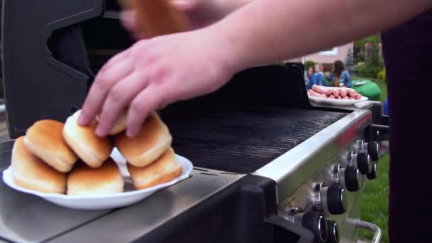 Чоловік готує хот-доги на грилі — стокове відео