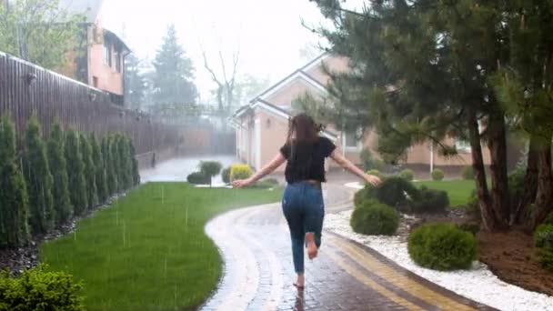 Mujer joven disfrutando de la lluvia en el jardín — Vídeos de Stock