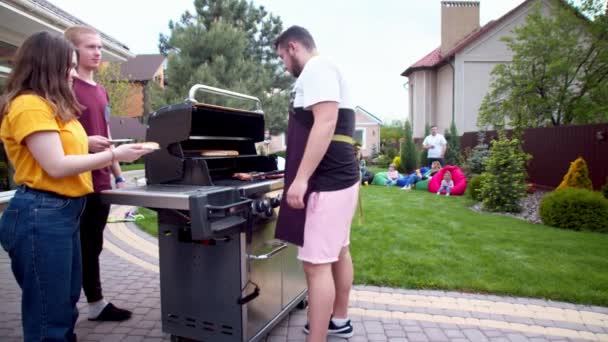 Muž podávající hot dogy mladým přátelům — Stock video