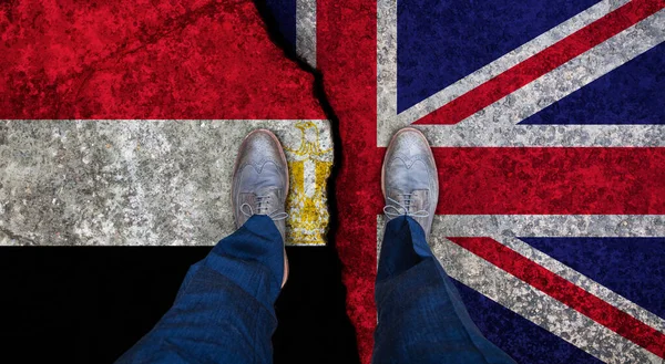 Obchodník stojí na popraskané vlajce Velké Británie a Egypta. Politický koncept — Stock fotografie