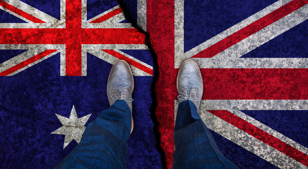 Деловой человек стоит на потрескавшемся флаге Великобритании и Австралии. Политическое понятие
