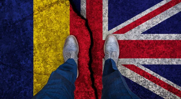 Uomo d'affari si erge sulla bandiera incrinata del Regno Unito e della Romania. Concetto politico — Foto Stock