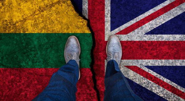 Деловой человек стоит на потрескавшемся флаге Великобритании и Литвы. Политическое понятие

