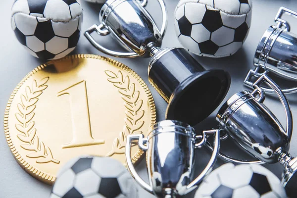 Gold first place winners medal and trophy with a soccer ball. Football success achievement concept