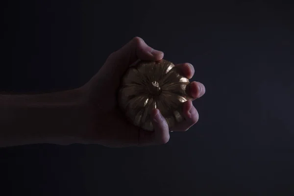 Een mannelijke hand die een gouden pompoen vasthoudt. spookachtige halloween achtergrond — Stockfoto