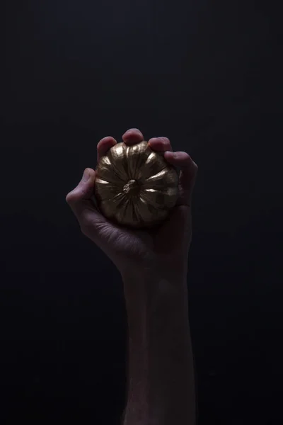 A male hand holding a golden pumpkin. Spooky halloween background — Stock Photo, Image