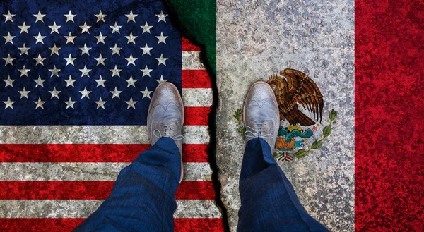Business man stands on cracked flags of USA and Mexico. Political concept