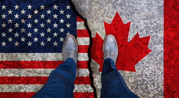 Business man stands on cracked flags of USA and Canada. Political concept