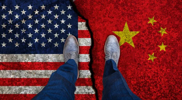 Business man stands on cracked flags of USA and China. Political concept — Stock Photo, Image
