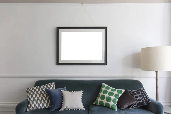 Empty picture frame hanging above a blue sofa in a living room — Stock Photo, Image