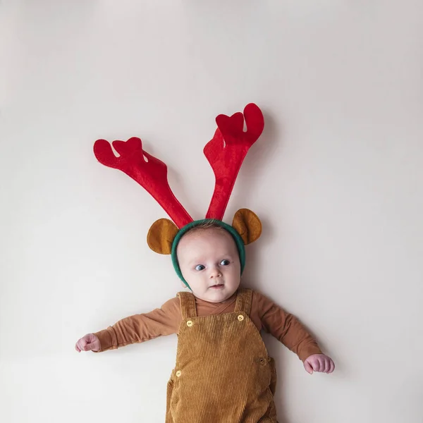 A cute two month old baby wearing festive christmas reindeer antlers