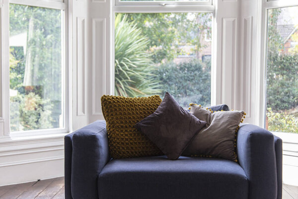 Комфортабельное синее кресло с подушками в современном интерьере гостиной
