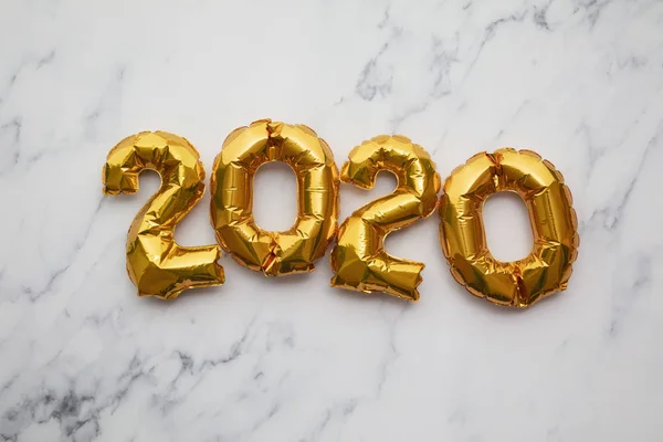 Celebración del Año Nuevo 2020. Globos de fiesta de lámina dorada sobre fondo de mármol —  Fotos de Stock