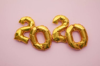 Yeni yıl 2020 kutlaması. Pastel pembe arka planda altın folyo parti balonları