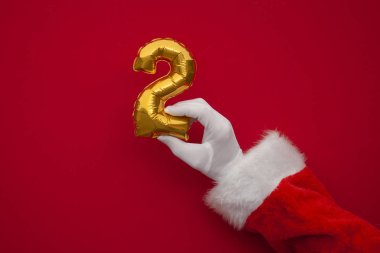 Noel 'in 12 günü. Noel Baba elleri kırmızı arka planda ikinci gün balonunu tutuyor.