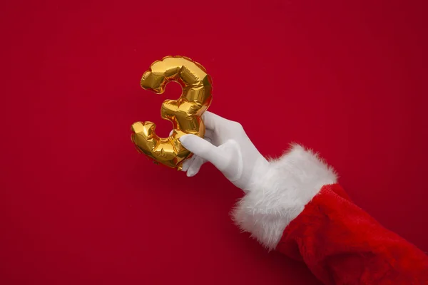 12 días de Navidad. Santa manos sosteniendo globo de 3er día sobre fondo rojo —  Fotos de Stock