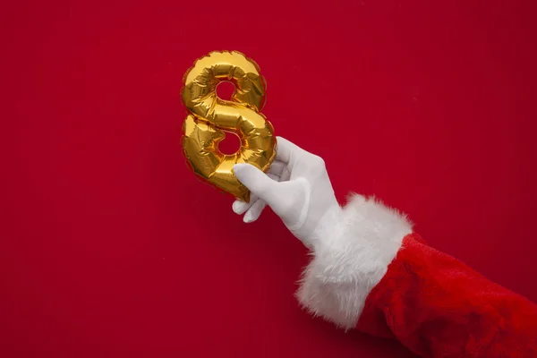 12 dni świąt. Santa ręce gospodarstwa 8 dzień balon na czerwonym tle — Zdjęcie stockowe