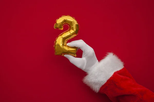 12 일간의 크리스마스. 붉은 배경에 둘째 날 풍선을 든 산타의 손 — 스톡 사진