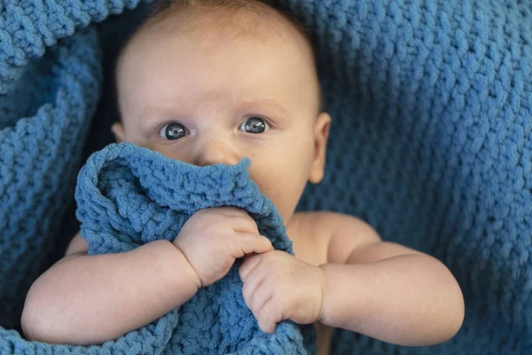 Um menino bonito abraçando um cobertor azul macio — Fotografia de Stock