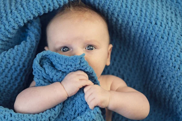 Un mignon bébé garçon étreignant une couverture bleue douce — Photo