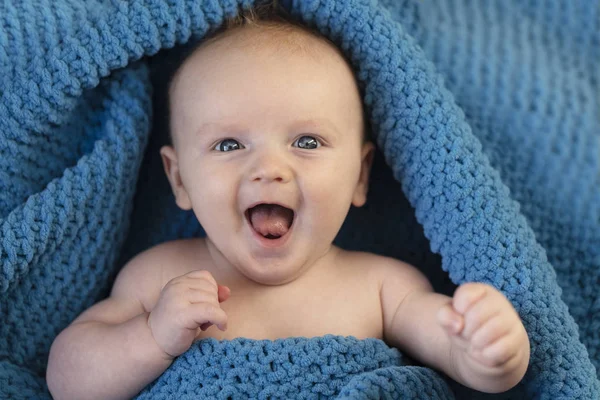 Ένα χαρούμενο μωρό που γελάει τυλιγμένο σε μια ζεστή κουβέρτα — Φωτογραφία Αρχείου