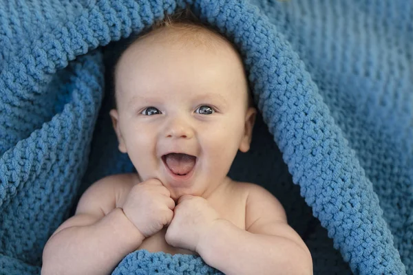 A happy laughing baby wrapped in a cosy bllue blanket — Stock Photo, Image