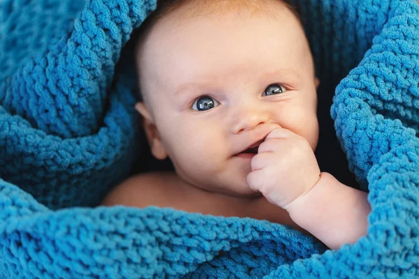 A cute baby boy wrapped in a cosy blue blanket looking at the camera — Stock Photo, Image